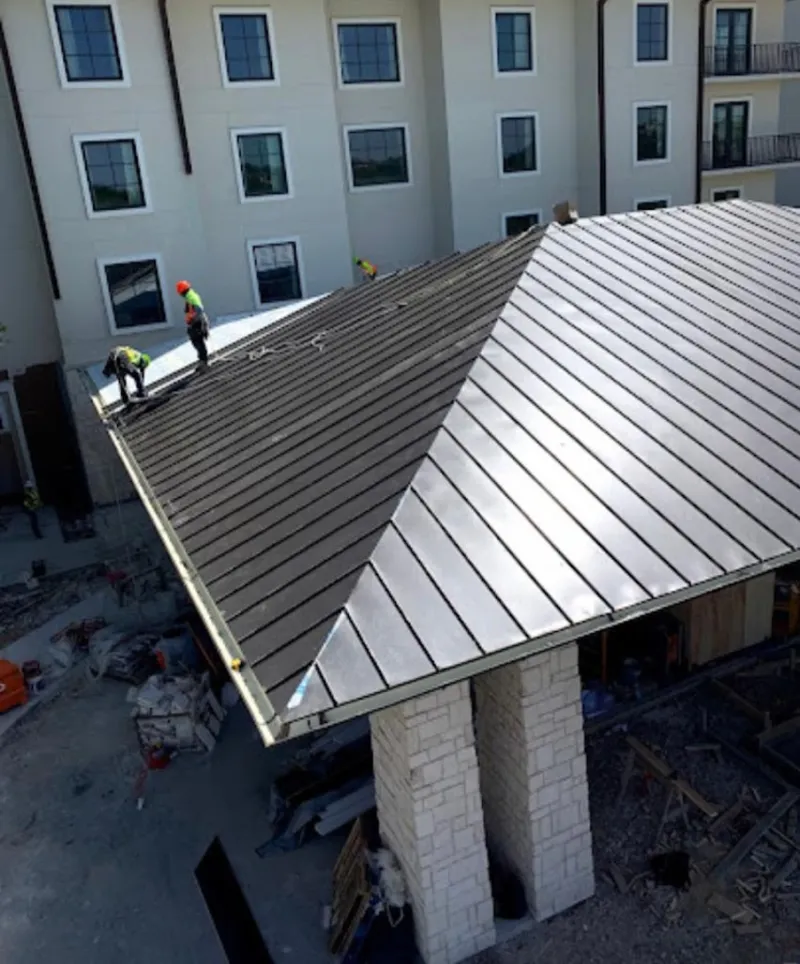 Crew installing standing seam metal roof panels on a commercial project in Woodway